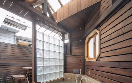 A wooden spa with a hot tub, wooden walls, and a large window.