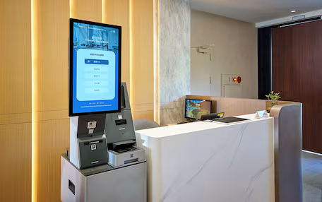A reception area with a digital display, a reception desk, a printer, and a clock.
