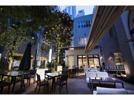 A hotel entrance with a brick facade, outdoor seating area, and potted plants.
