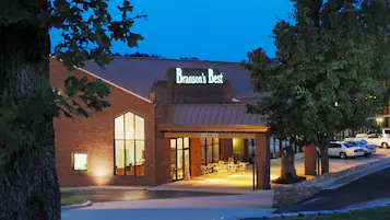 A brick building with a sign reading "Branson's Best" and a covered entrance with tables and chairs.