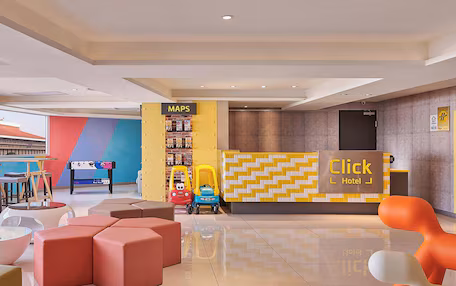 A hotel lobby with a reception desk, colorful seating, and a children's play area.