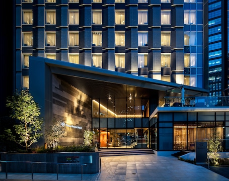A hotel entrance with a brick facade, outdoor seating area, and potted plants.