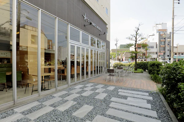 A hotel entrance with a brick facade, outdoor seating area, and potted plants.