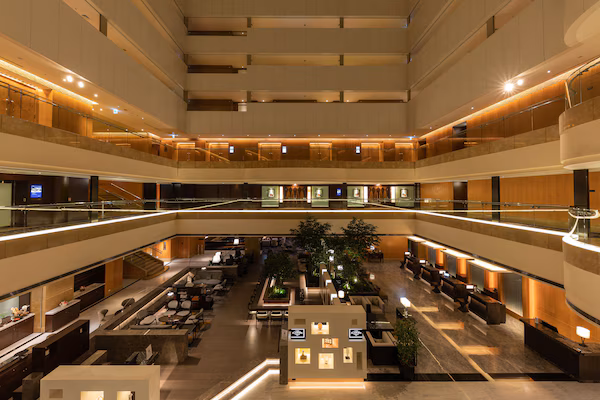 A multi-level hotel lobby with a central atrium, seating areas, and a staircase.
