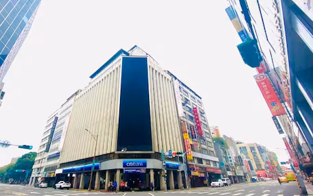 A modern building with a prominent vertical feature, likely a bank or corporate headquarters, surrounded by other commercial buildings and busy streets.