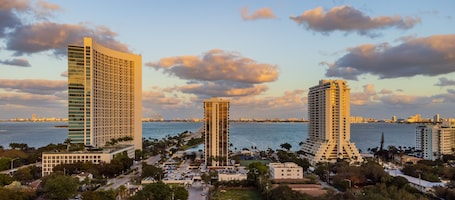 A high-rise hotel with a modern design, located near a waterfront with a view of the sea and city skyline.
