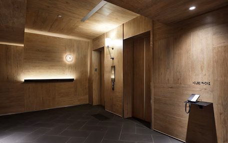 A wooden interior with a reception desk, an elevator, and a wall-mounted phone.